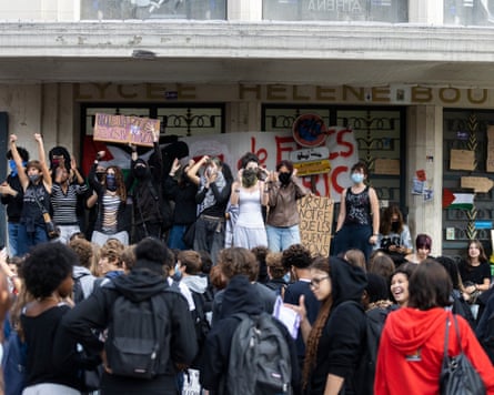 Crowd of students at school entrance, some with placards