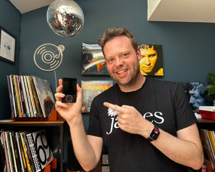 A man holds up an MP3 player and smiles