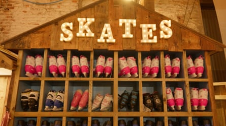 A wooden cabinet full of ice skates with an illuminated sign saying “Skates” above