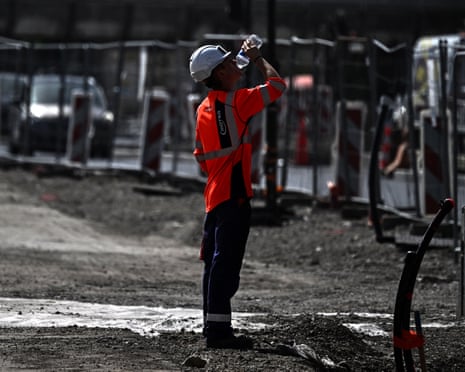 A worker drinks water from a bottle at a construction site