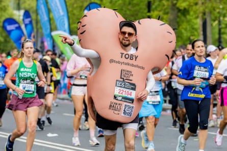 A man running a marathon in a giant testicles costume surrounded by other runners
