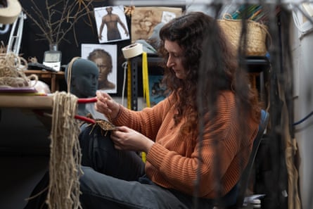 Wētā Workshop's lead weaver Jasmin van Lith weaves a small intricate object in a cluttered studio