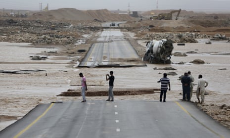 People look at a road torn apart by Cyclone Merkunu in Salalah, Oman
