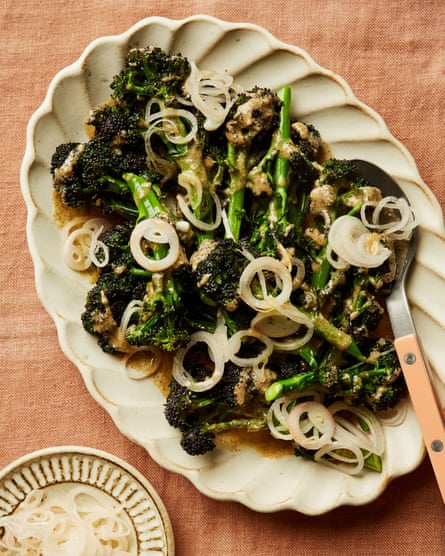 Chantelle Nicholson’s purple sprouting broccoli, almond butter and pickled shallots on a plate, with a smaller plate with white matter upon it – ringed shallots – and a brown sauce or dip – almond butter – in a little bowl.