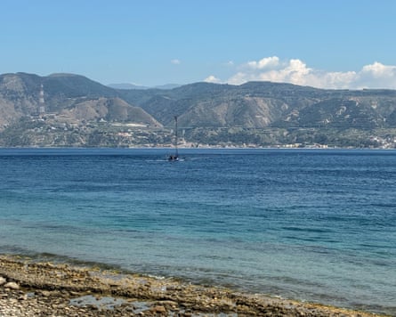 View across the strait of Messina towards the mountainous coastline of southern Italy, with clear blue water in the foreground.