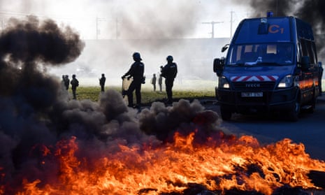 Gendarmes walk next to burning tyres as they try to remove a blockade of gilets jaunes protesters in Aimargues, near Montpellier
