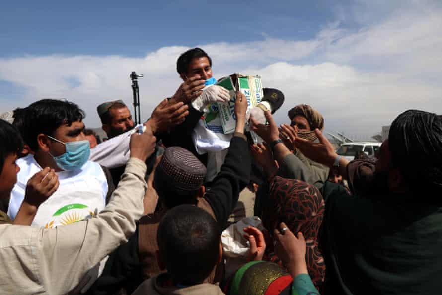 People gather to collect masks, gloves and disinfectants distributed to the public, in Herat, Afghanistan, 15 March 2020.