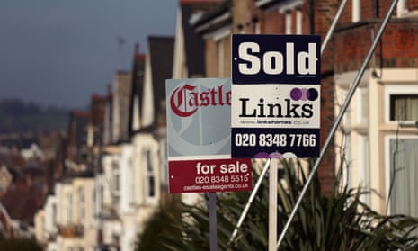 Estate agent boards outside houses on a residential street.