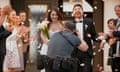 Photographer taking picture of newlywed bride and groom as they leave church.