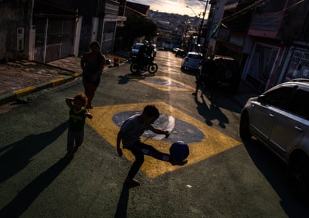 A boy plays with a ball on a street painted with the Brazilian flag in Osasco, Brazil.