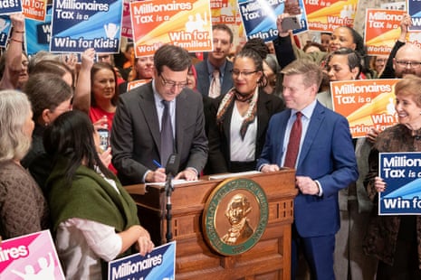 A legislator signs Senate Bill 6346 at a podium, surrounded by a cheering crowd with signs
