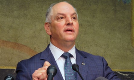 Middle-aged white man in good lighting in blue suit, gesturing with right right behind lectern and speaking.