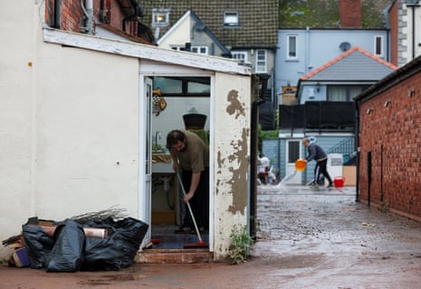 A man cleans a house after severe flooding caused by Storm Claudia in Monmouth, Wales, on 16 November 2025.