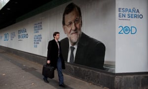 A man walks past a giant poster of Spain’s PM and PP leader Mariano Rajoy