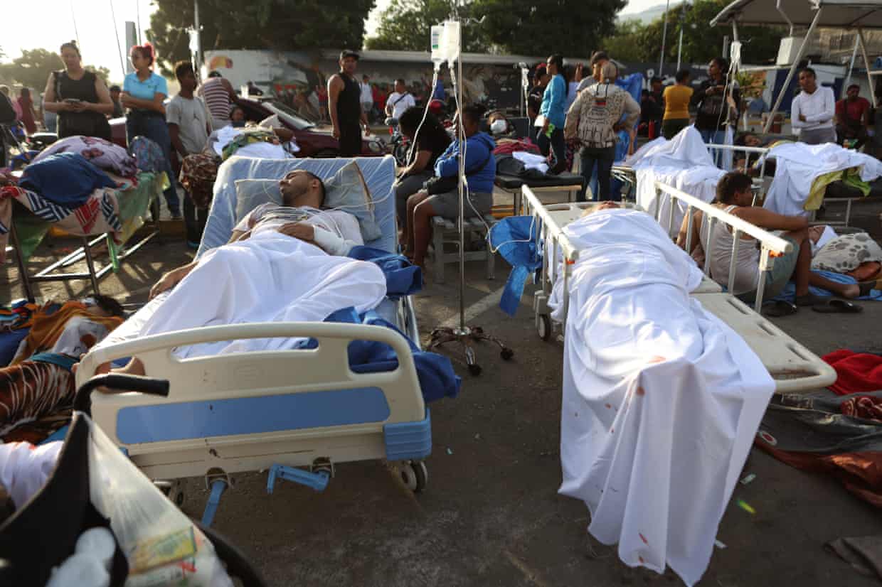 Patients lie outside a hospital evacuated after it was damaged in an earthquake in Catia La Mar.
