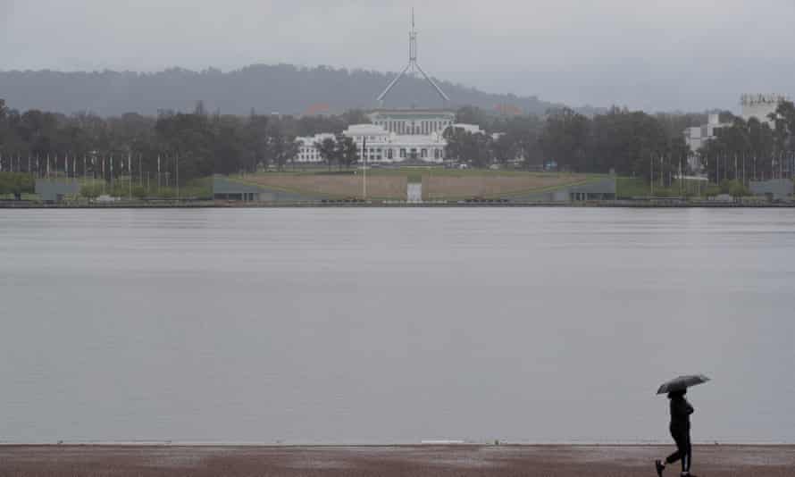 People walk around Lake Burley Griffin in Canberra as rain falls
