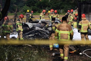 Firefighters and military officers work at the scene of crashed navy plane