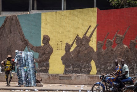 A motorcyclist rides past a monument in support of the Malian army in Bamako