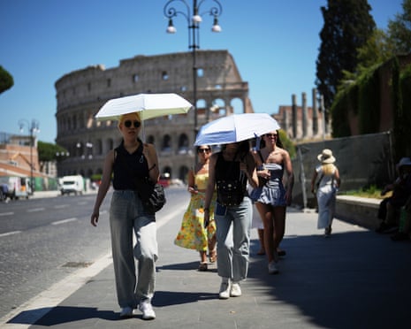 People use umbrellas in hot weather to shelter from the sun while walking past the Colosseum, in Rome.