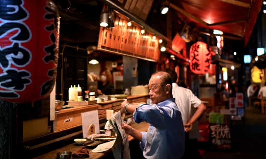 A man reading a newspaper in a Shimbashi izakaya in June last year.