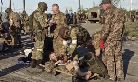 Russian servicemen frisk Ukrainian soldiers as they are evacuated from the besieged Azovstal steel plant in Mariupol.