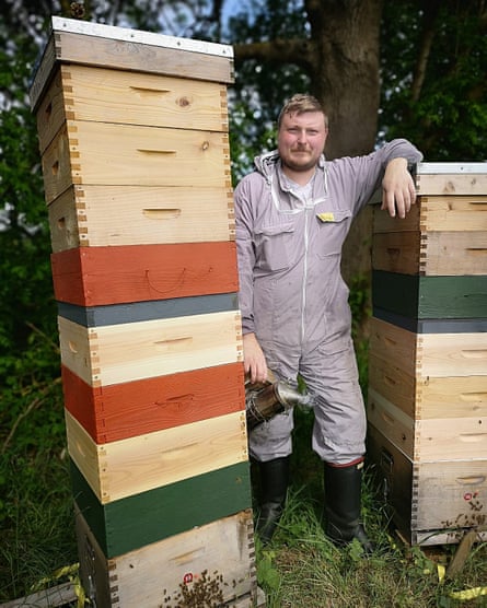 Paul Horton standing between two of his beehives