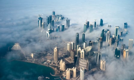 An aerial view of high-rise buildings emerging through fog covering the skyline of Doha.