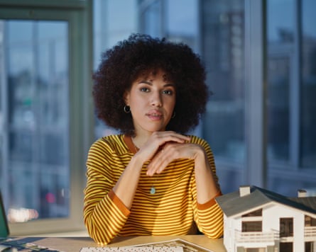 Person posing in modern office with building model on desk