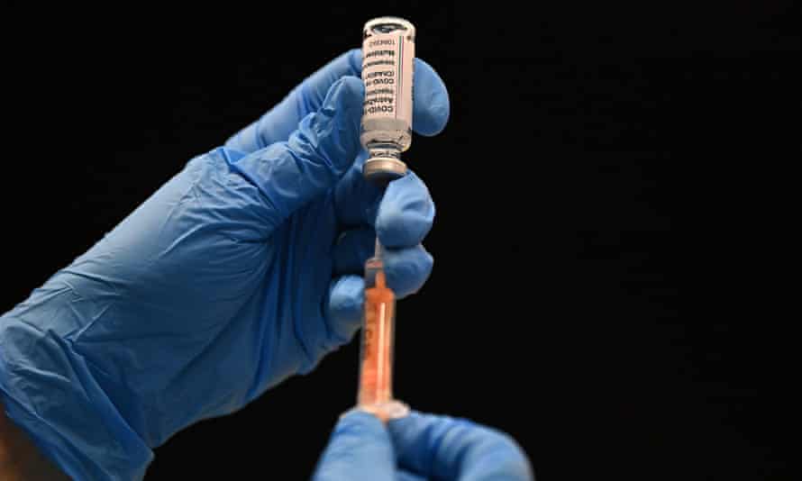 Gloved hands fill a syringe