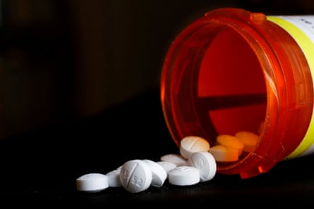 Opioid pills on a surface next to a prescription pill bottle on its side