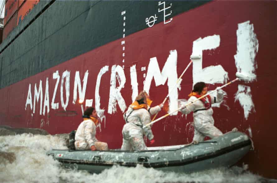 Activists in protective suits painting “Amazon Crime!” in white paint on the freighter MV Enif ship which was loaded with timber from Brazil. The activists are painting the side of the ship from an inflatable.