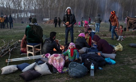 People who have fled Syria rest as they wait to cross the border from Turkey into Greece