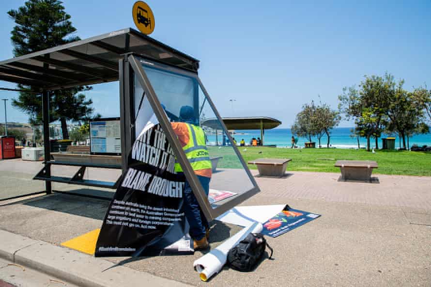 A volunteer pulls advertising from a Sydney bus shelter, replacing it with a political poster.