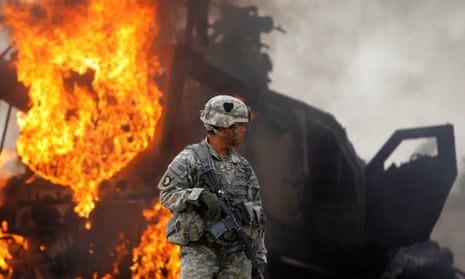A US army captain stands near a burning armored vehicle destroyed by an improvised explosive device (IED) in the Arghandab Valley north of Kandahar, Afghanistan, in 2010. 