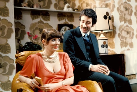 Alison Steadman sitting in an armchair and Tim Stern resting on the arm in a 70s setting