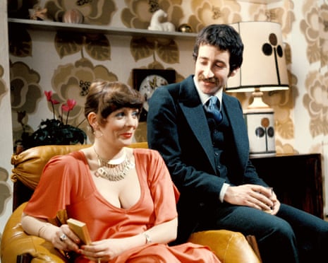 Alison Steadman and Tim Stern smiling as they sit on an armchair in Abigail's Party