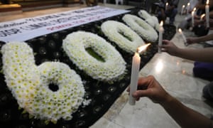 Women hold candles beside a floral arrangement symbolising the number of dead during super Typhoon Haiyan during a Catholic Mass in Manila