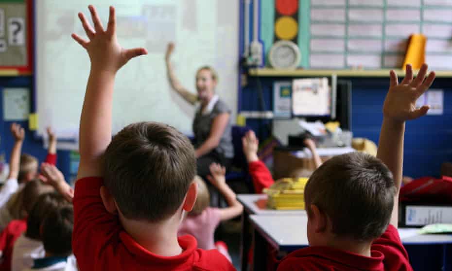 Children raise their hands to answer questions in a primary school