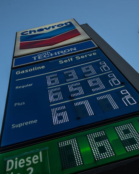A Chevron gas station price sign displays fuel prices in LED digits against a blue sky
