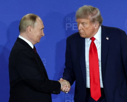 Trump and Putin shake hands, one looking down, against a blue backdrop