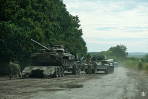 Ukrainian soldiers load an abandoned Russian military vehicle on to a trailer during the Ukrainian army counteroffensive in Kharkiv, as the Russian military invasion of Ukraine continues