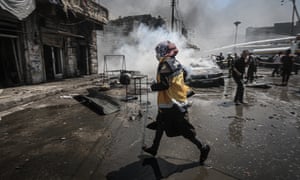 A civil defence worker helps carry out a rescue operation after airstrikes on the town of Arihah in Idlib province, in July
