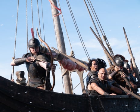 Matt Damon as Odysseus, wearing armour and a helmet, aims a bow aboard a ship with rigging