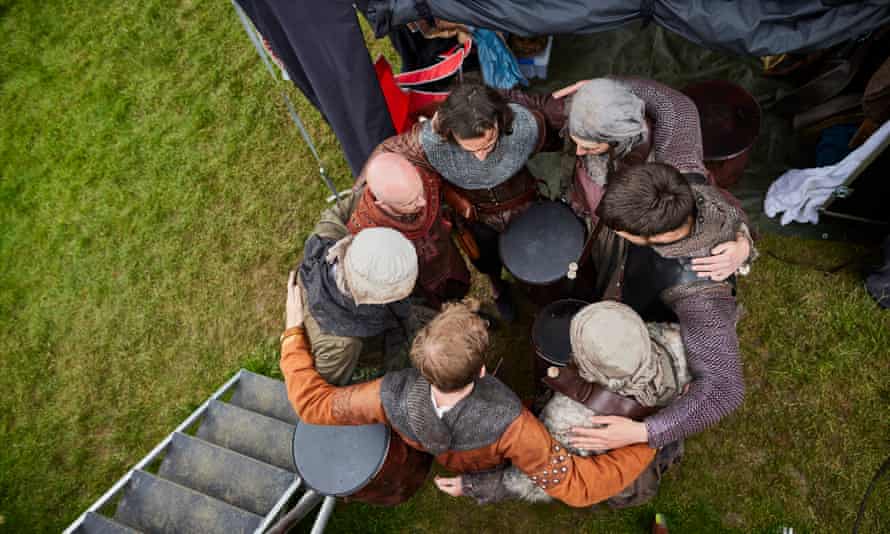 Actors huddle before beginning a costumed run-through during rehearsals at the Stanley Hall base camp in Essex