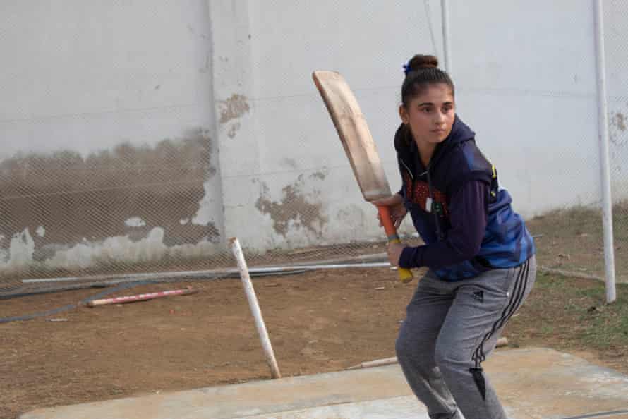 A girl lifts her bat as she awaits a delivery in the nets