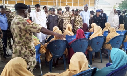 Kidnapped schoolgirls sit down during a handover to government officials in Maiduguri on 21 March.