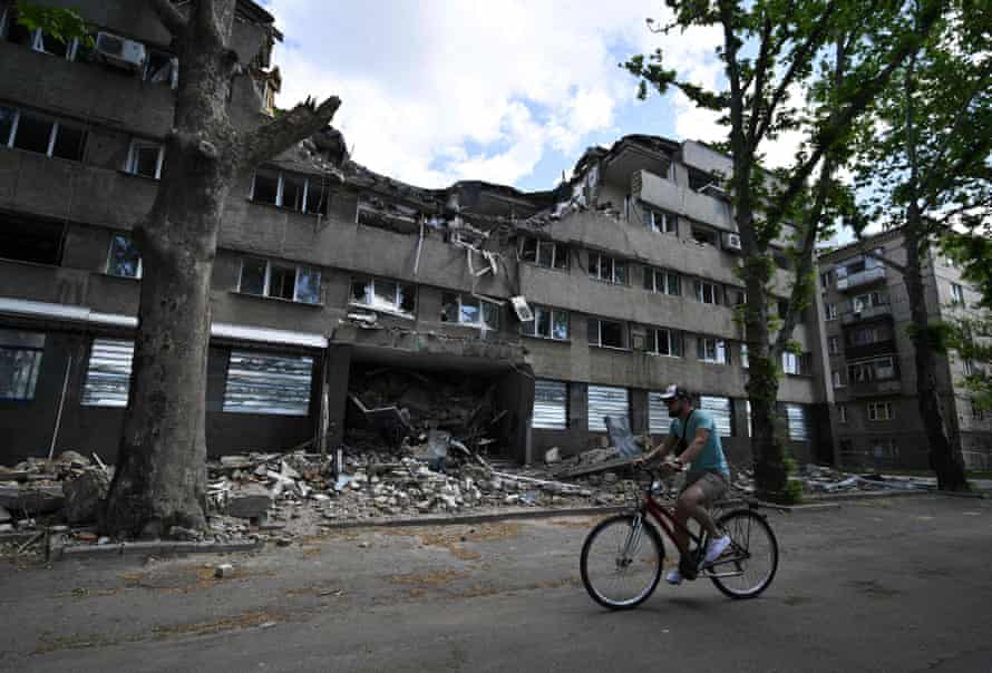 A man rides his bicycle past a building of hotel Ingul, destroyed by a Russian air strike in March, in the southern Ukrainian city of Mykolaiv.