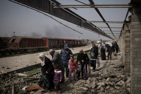 Civilians flee through a destroyed train station during fighting between Iraqi security forces and Islamic State militants, on the western side of Mosul