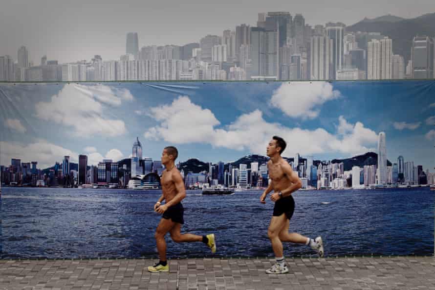 Two men run past a billboard in Hong Kong