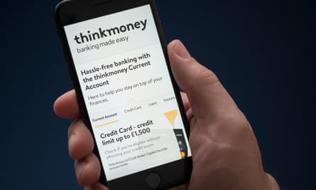 A man looks at his iPhone, which displays the Thinkmoney logo